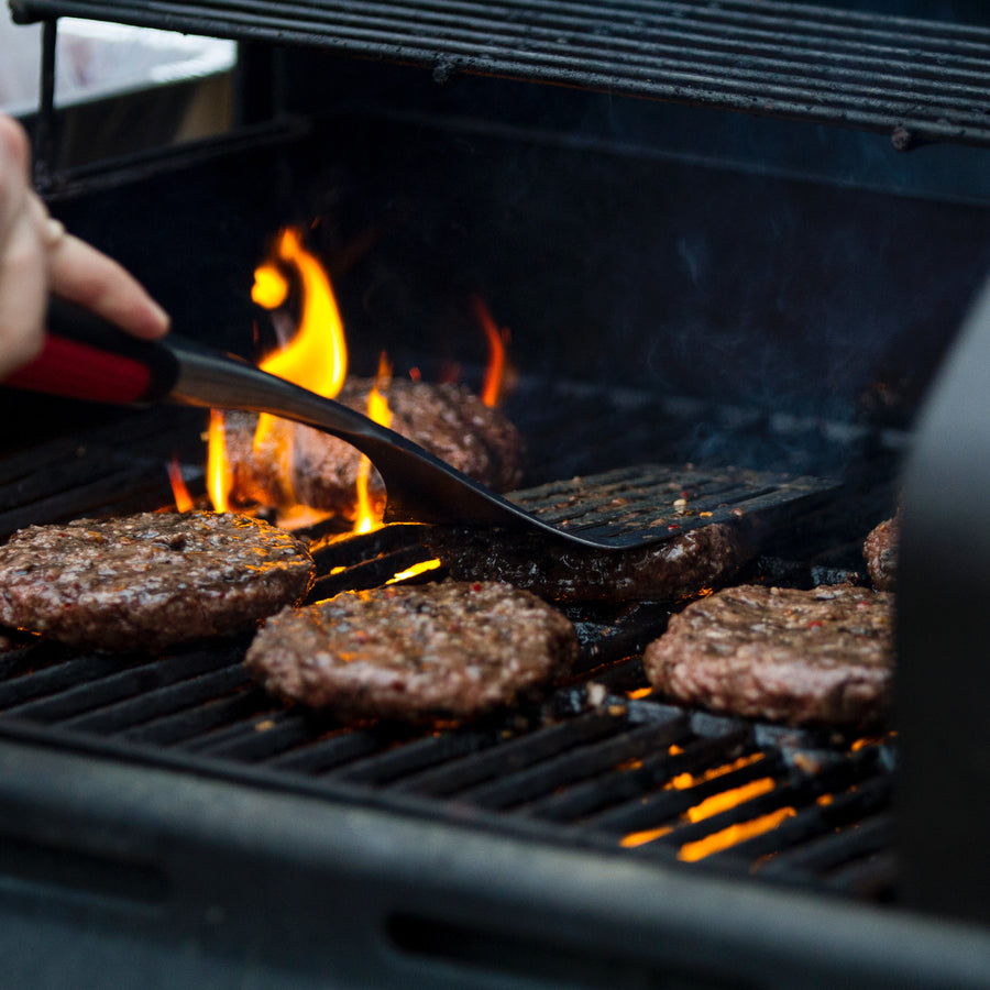 Hereford beef burgers cooking over flames on a barbecue