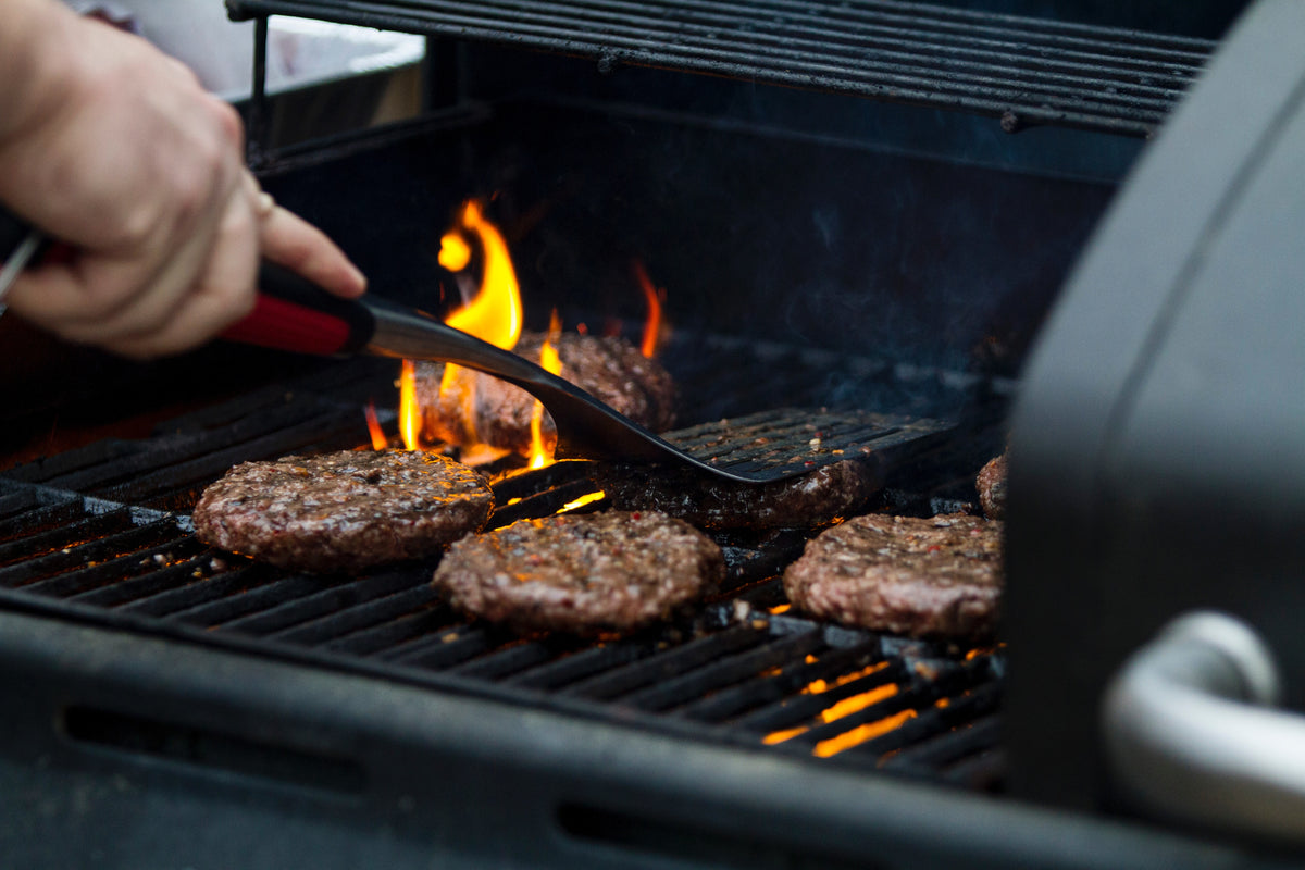 Hereford beef burgers cooking over flames on a barbecue
