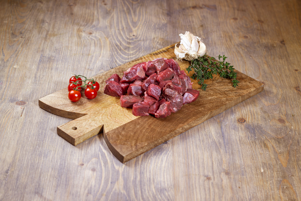 Diced Hereford stewing beef on a wooden board